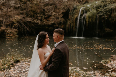 Rear view of couple standing against lake