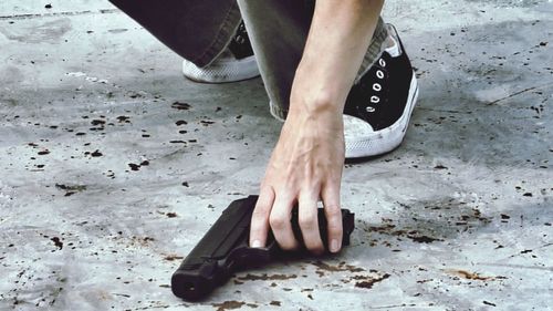 Low section of person picking up gun