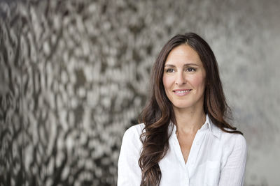 Portrait of confident businesswoman in front of rippled wall