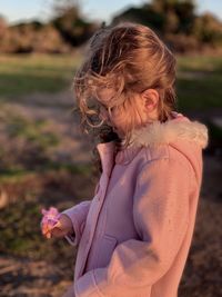 Woman wearing warm clothing standing on land at sunset