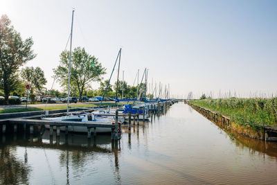 Sailboats moored in river against sky