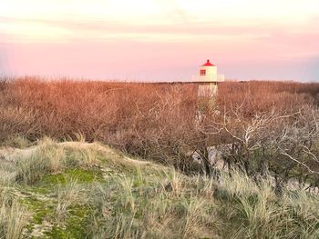 Lighthouse by sea against sky during sunset