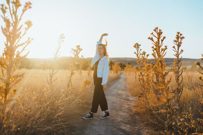 Rear view of woman standing on field against clear sky