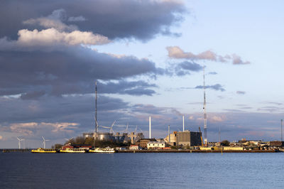 Sailboats in sea by buildings against sky