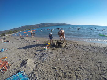 People on beach against clear sky