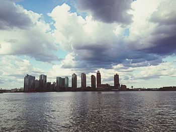 Skyscrapers in city against cloudy sky