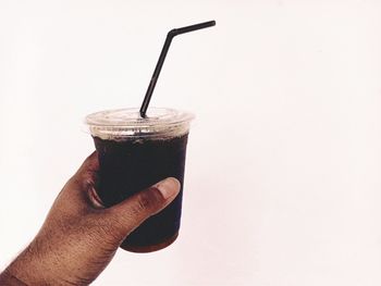 Cropped image of hand holding coffee cup against white background