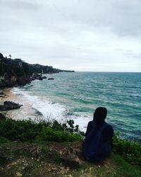 Rear view of man sitting on shore