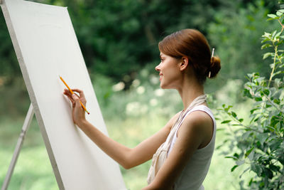 Side view of young woman holding plant