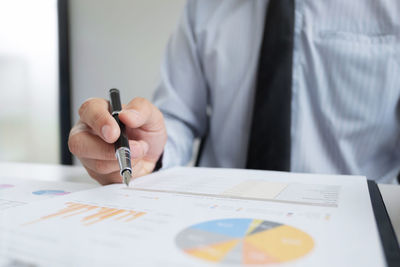 Midsection of man holding paper with text on table