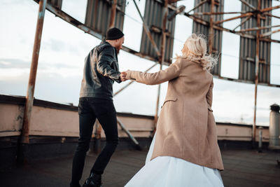 Rear view of couple standing on railing