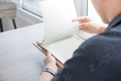 Midsection of woman reading book on table