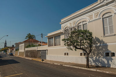 Old ornate townhouse in an empty street with trees on sidewalk in a sunny day at são manuel, brazil.