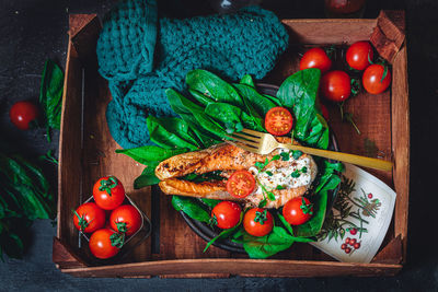 A plate with fresh green raw spinach and fried wild salmon, tomatoes and cream cheese sauce 
