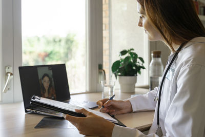 Young female doctor discussing with patient during online consultation