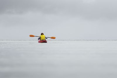 Person kayak in sea against sky