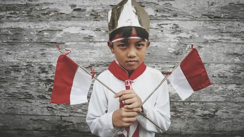 Portrait of boy holding flag against weathered wall