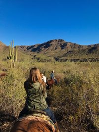 Rear view of woman photographing on field against clear sky