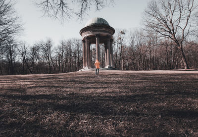 Rear view of man standing by built structure against trees