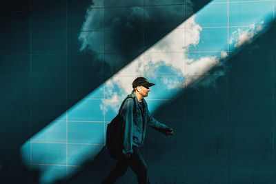 Side view of young man looking away against wall