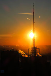 Silhouette of communications tower against sky during sunset