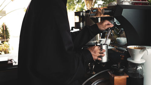 Midsection of barista preparing coffee at cafe