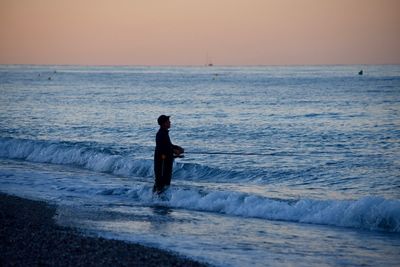 Side view of silhouette man fishing in sea