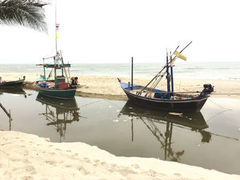 Boat moored on beach against clear sky