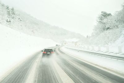 Car on snow covered road against sky