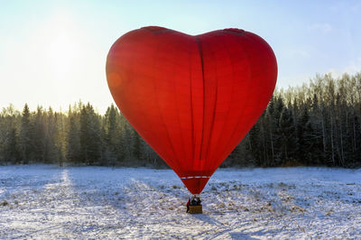 Hot air balloon flying over snow covered field