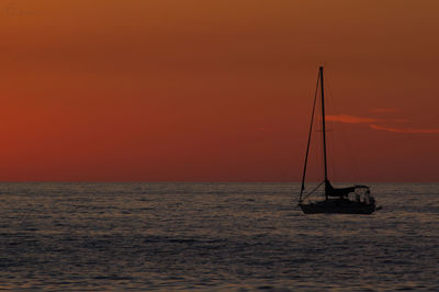 Sailboat sailing on sea against sky during sunset