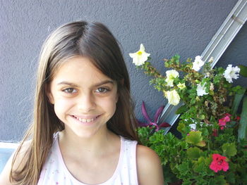 Portrait of smiling young woman against white flowering plants