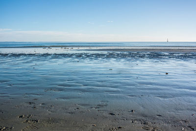 View of calm beach against blue sky