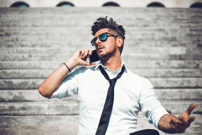 Low angle view of man talking on phone while sitting on steps