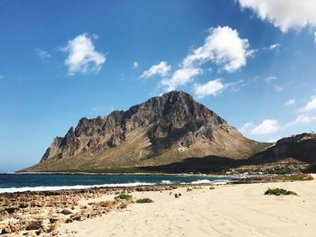 Scenic view of beach by mountains against sky