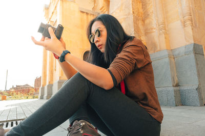 Woman with camera sitting at ancient building