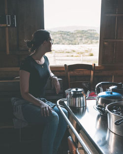 Side view of woman sitting at home