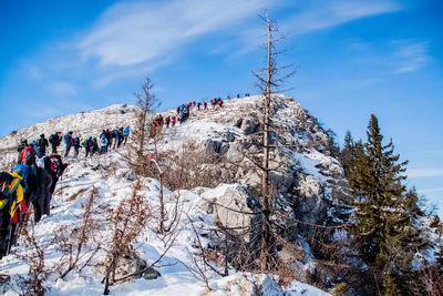 Group of people on snow covered mountain against sky