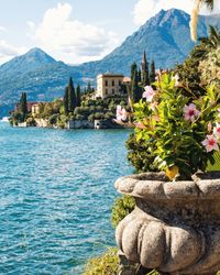 Scenic view of lake and rocks by buildings against sky