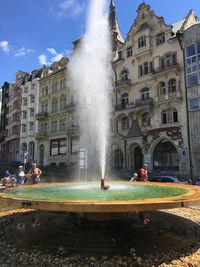 Fountain in city against sky