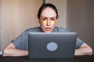 Portrait of young woman using laptop while sitting on table