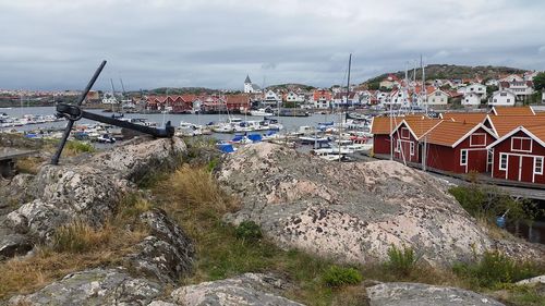 Sailboats moored on sea by buildings against sky