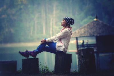 Side view of young woman sitting on tree stumps