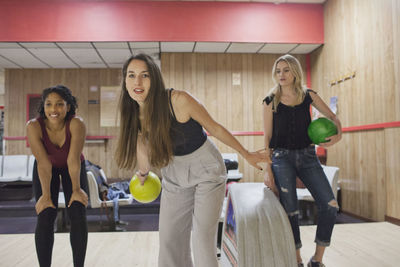 A young woman bowling with friends.