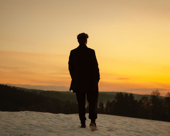 Silhouette man standing on street against sky during sunset