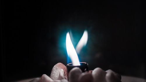 Close-up of hand holding lit candle