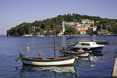 Boats moored in sea against clear blue sky