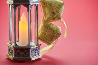 Close-up of lit candle on table against wall