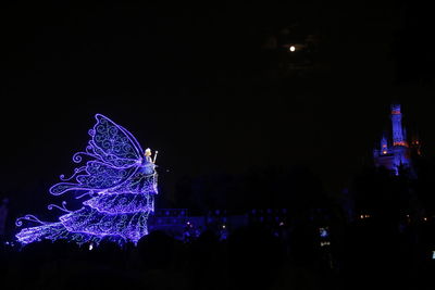 Illuminated christmas lights in city against sky at night