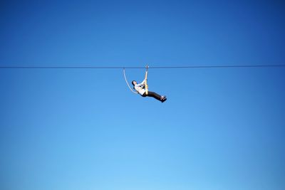 Low angle view of person against clear blue sky